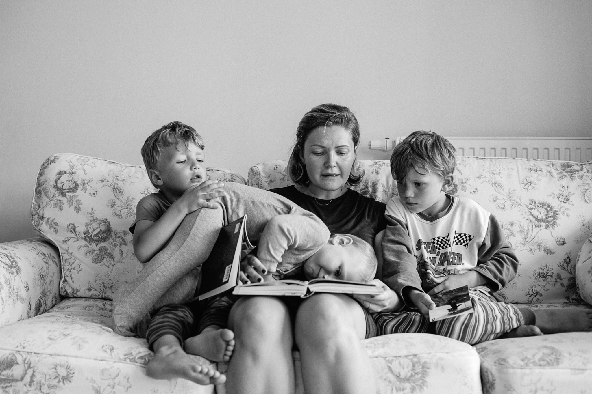 Mutter mit 3 Söhnen beim Buchvorlesen